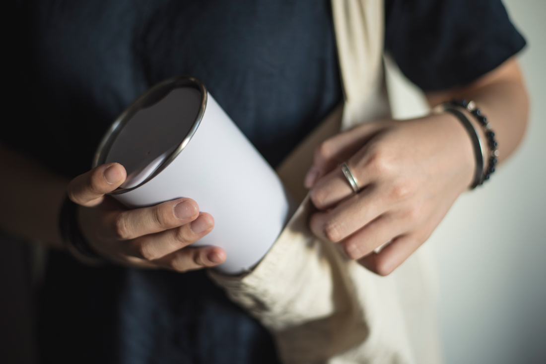 Person putting a reusable cup back into a canvas tote bag